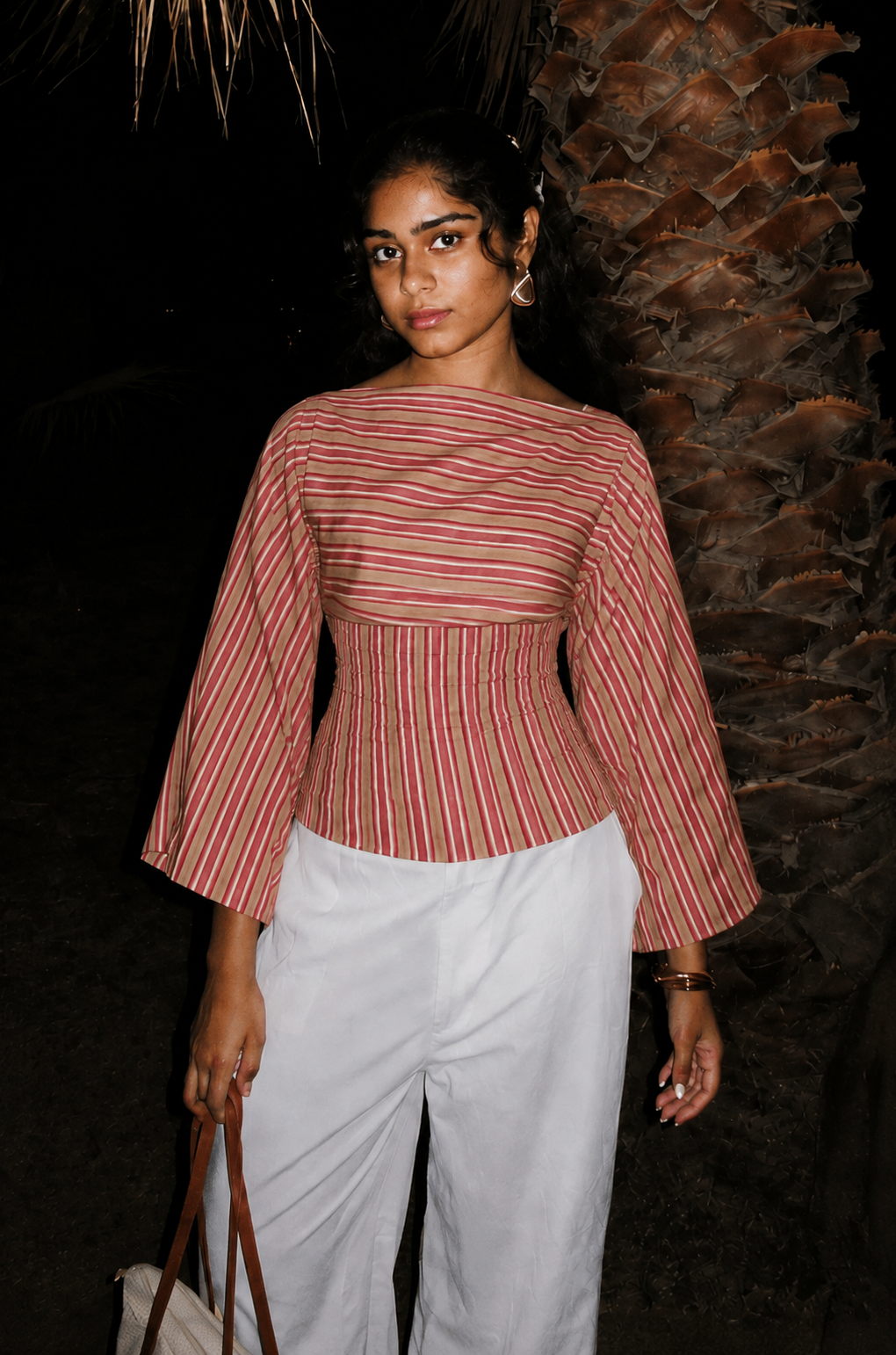 Woman wearing the Rosé pink and rust striped tie-back top with long bell sleeves