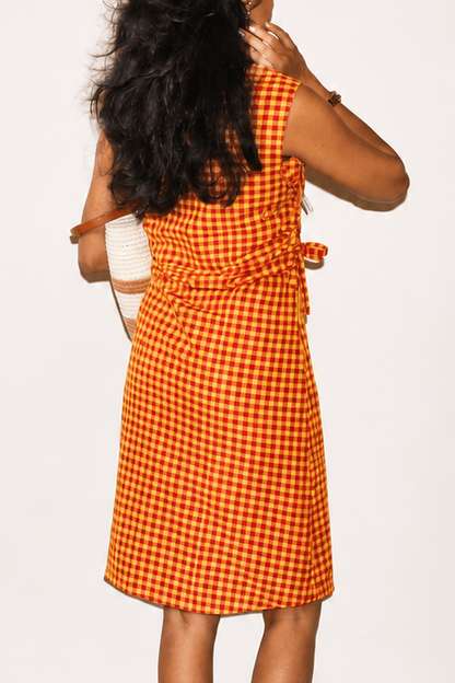 Woman wearing an orange checkered dress with a plain background