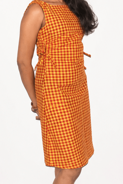 Orange checkered dress worn by a person on a white background