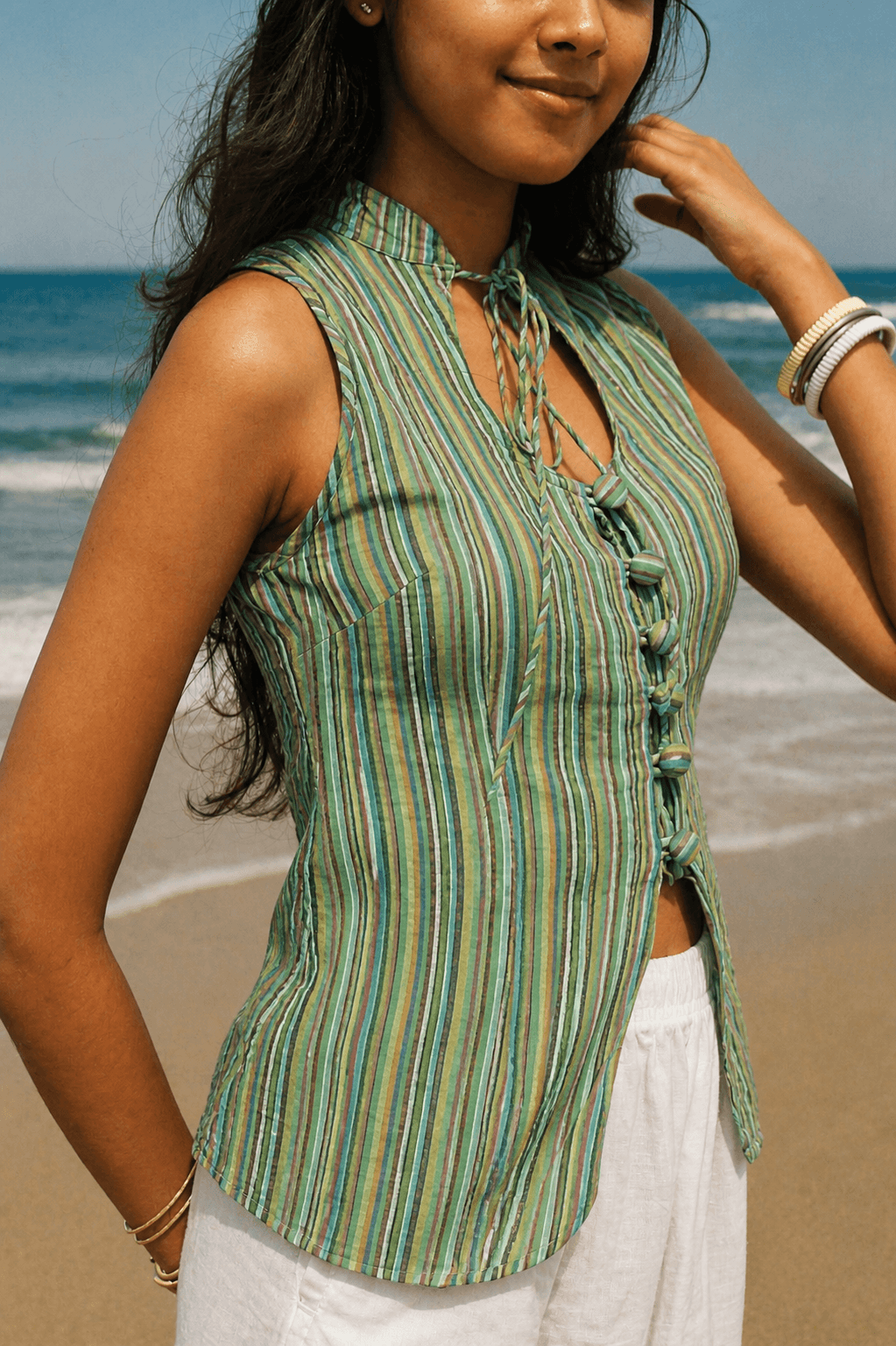 Woman wearing a green striped sleeveless top on a beach