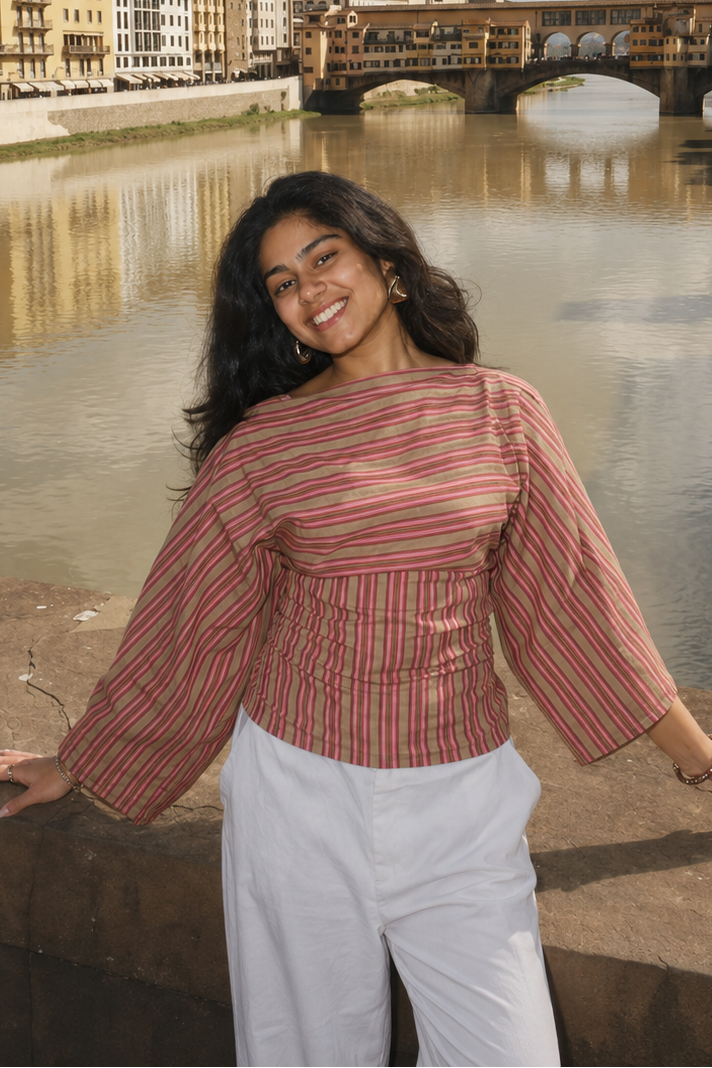 Woman in the Rose Stripe Tie-Back Top and white trousers beside a river with an old stone bridge