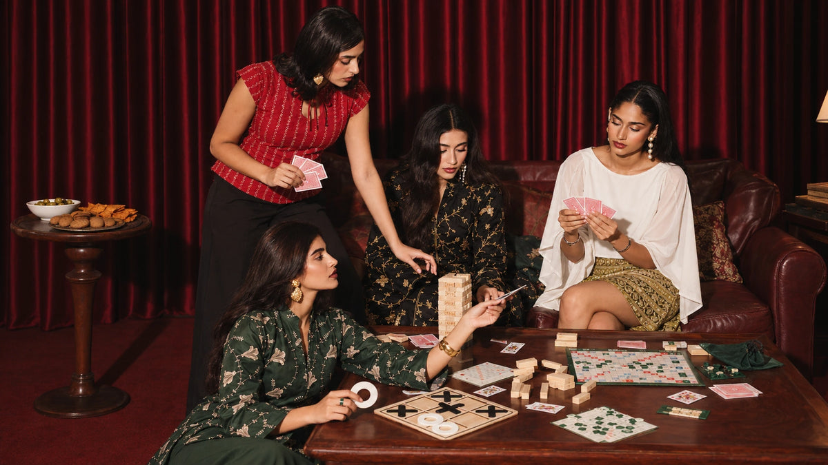 mazo Jig Jig festive collection: four women in embroidered tops, a skirt and dresses around a table playing cards