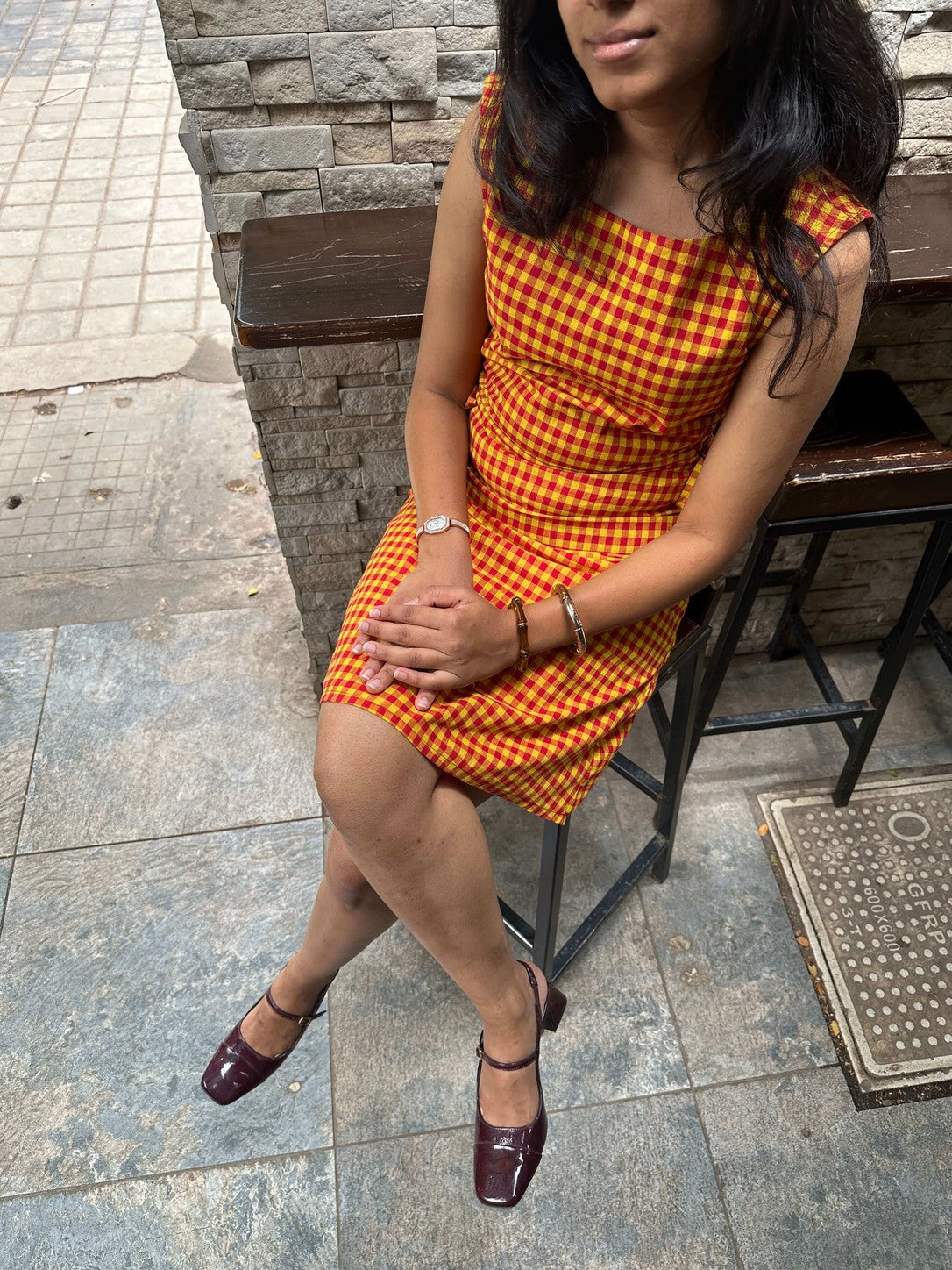Woman seated wearing the Summer Jam orange gingham midi dress