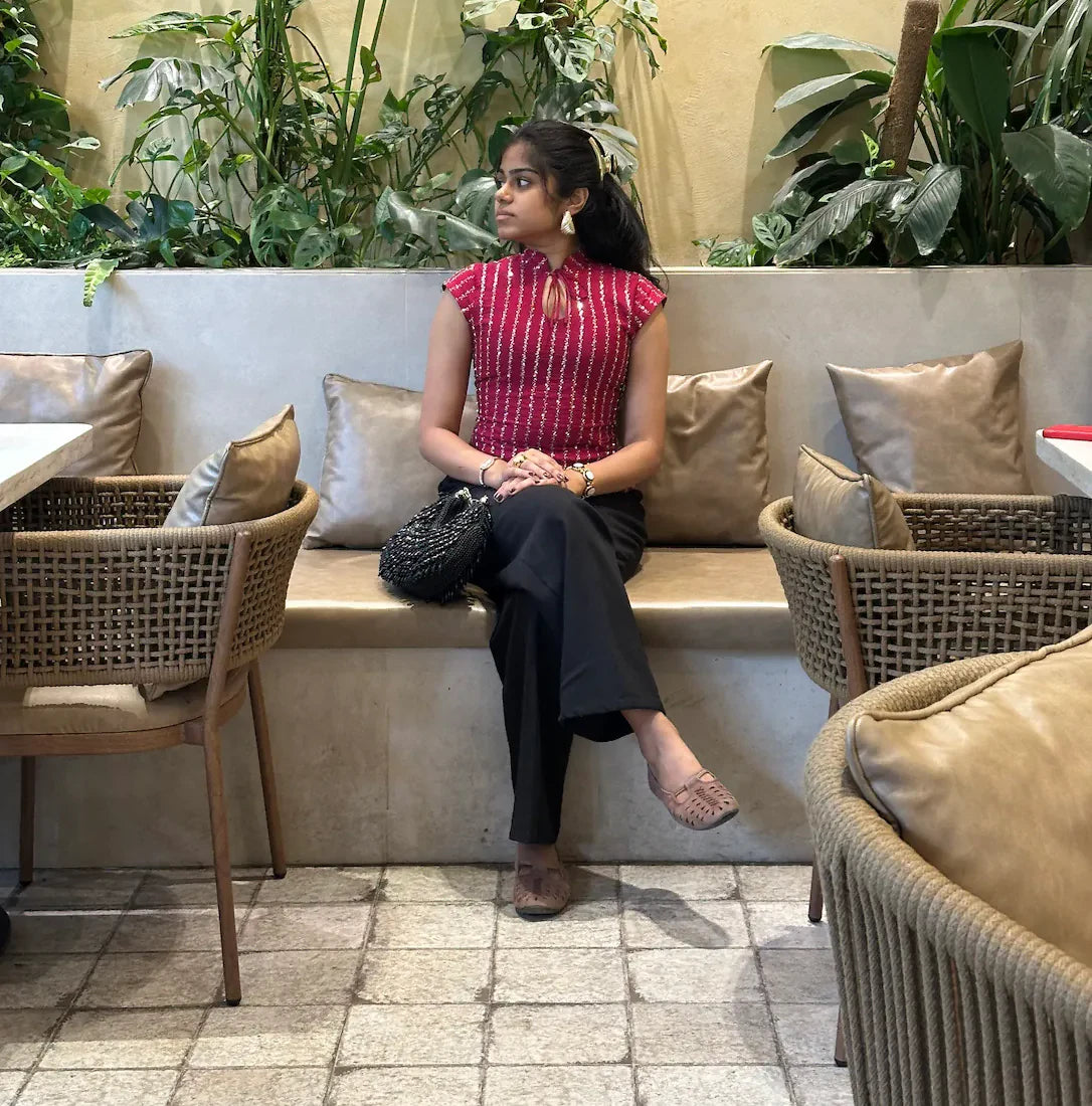 mazo Mirchi red embroidered top worn with black trousers in a cafe
