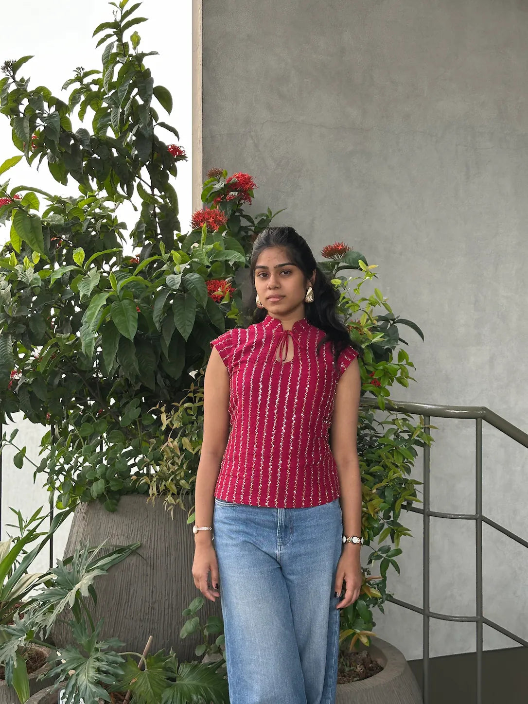 mazo Mirchi red embroidered top worn with blue jeans among plants