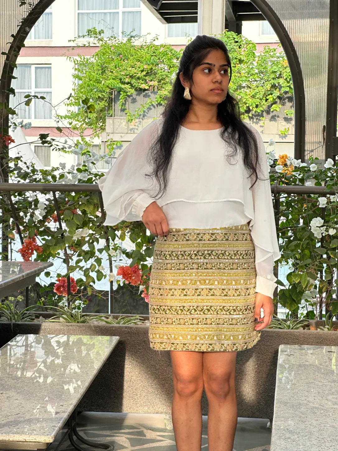 mazo Tamasha embroidered mini skirt with a white top on a garden terrace