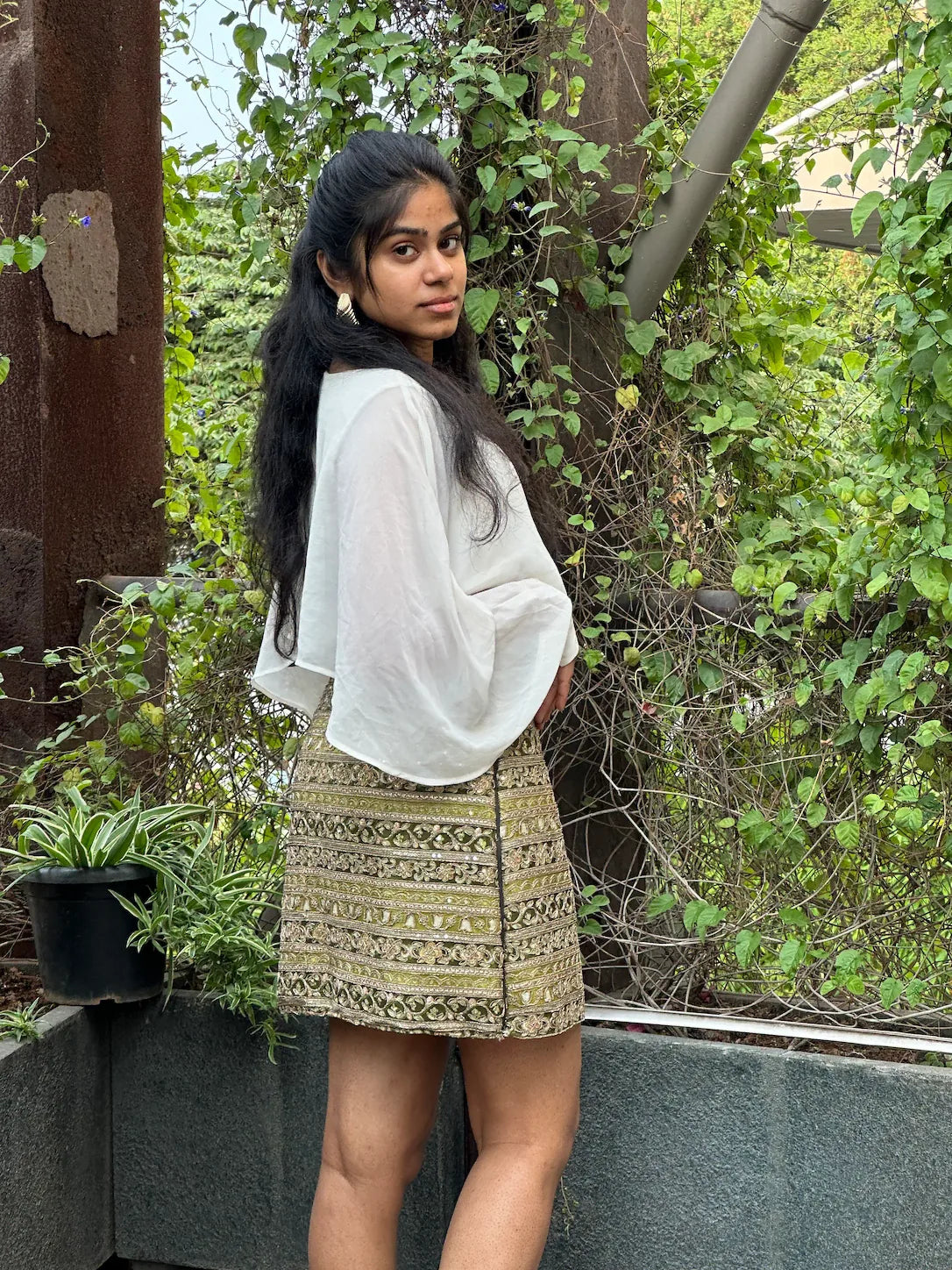 mazo Tamasha embroidered mini skirt worn with a white top in a leafy garden