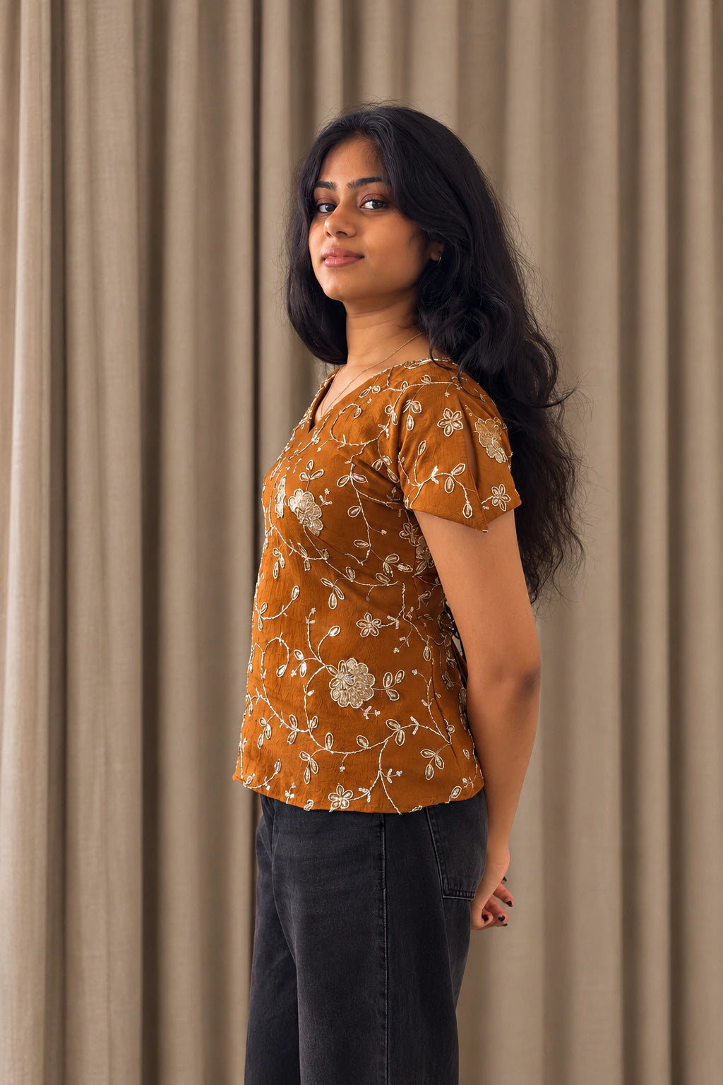 mazo Pataka top, side view of the V neck and petal sleeve, worn with black wide leg jeans