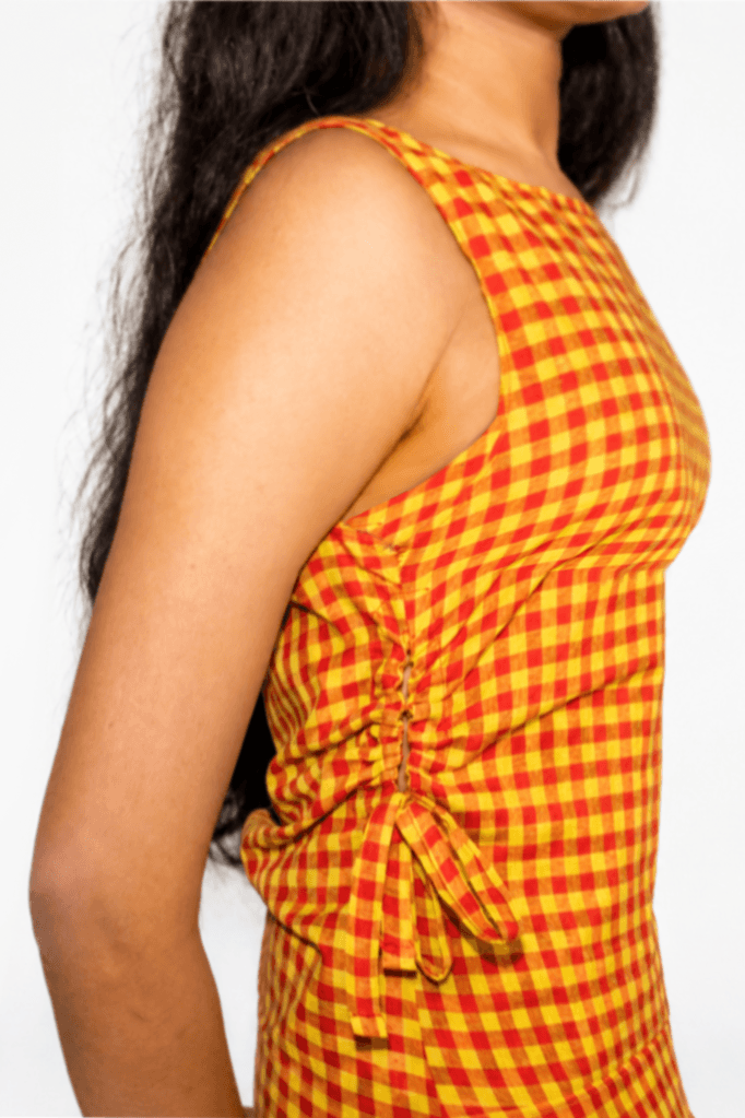 Woman wearing a yellow and red checkered dress with a white background
